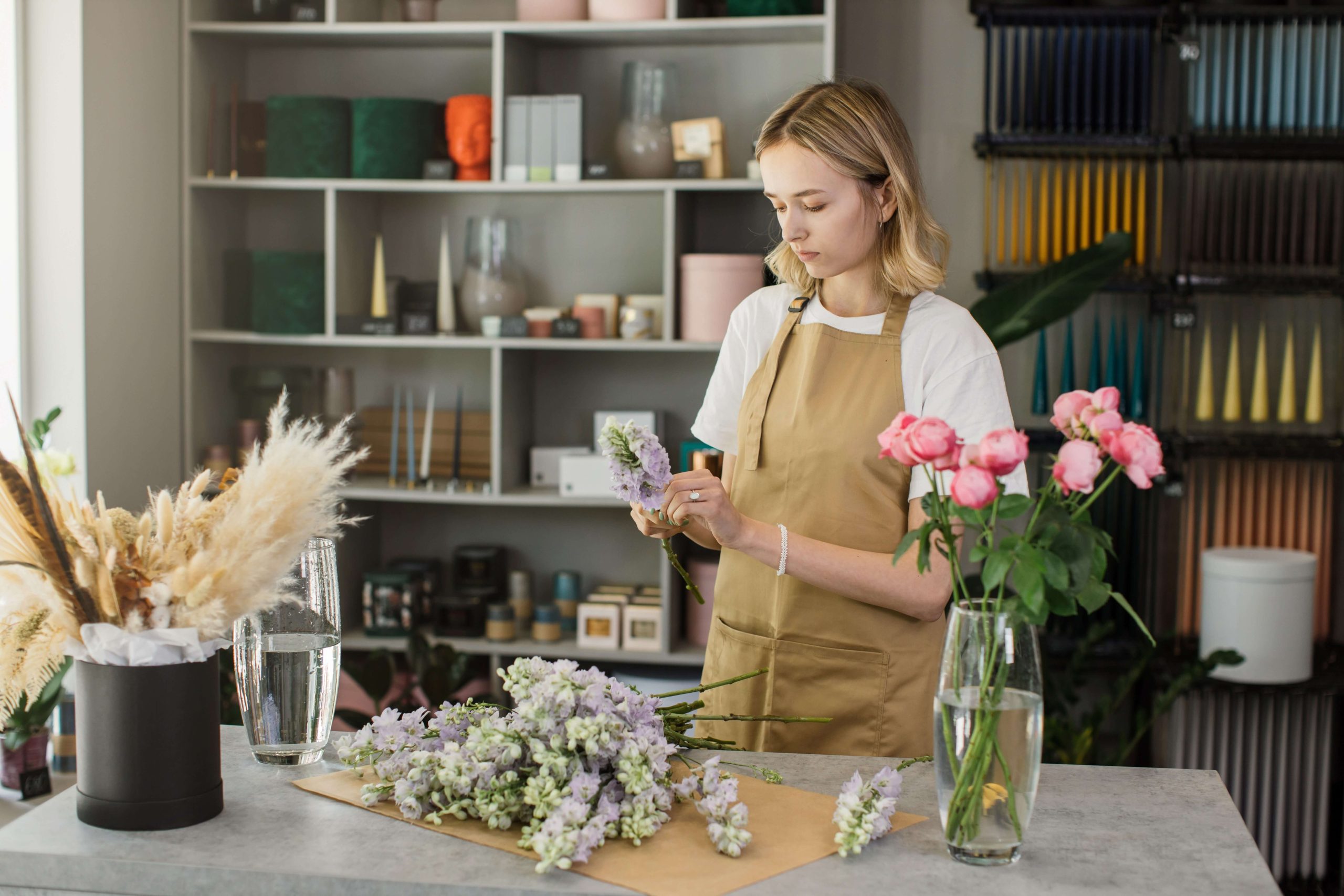 Florista trabajando con flores frescas en su tienda, optimizando el uso del espacio de trabajo con estanterías organizadas.